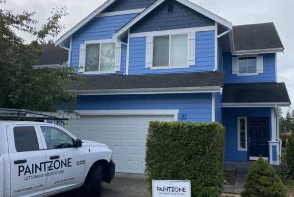 Image displays the charming exterior of a Queen Anne style home, painted in a delicate light blue hue. Highlighting its architectural details are navy blue accent shingles that add depth and character to the structure. The navy blue contrasts brilliantly with the main color, enhancing the building's vintage charm. White trims outline the windows and doors, providing a crisp contrast that frames the home's features. This combination of colors brings a fresh, yet traditional appeal to the home, reflecting the elegance of Queen Anne style.
