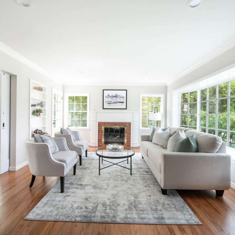 Image displays the interior of a living room in a Magnolia home, where the walls, ceilings, and trims have been freshly painted. The uniform color scheme creates a cohesive and serene atmosphere, harmonizing with the room's furnishings and decor. The painted trims outline the architectural features, adding definition to the space. The lighting in the image beautifully illuminates the painted surfaces, showcasing the quality of the paintwork. The overall view provides an inviting glimpse into this stylish Magnolia home.