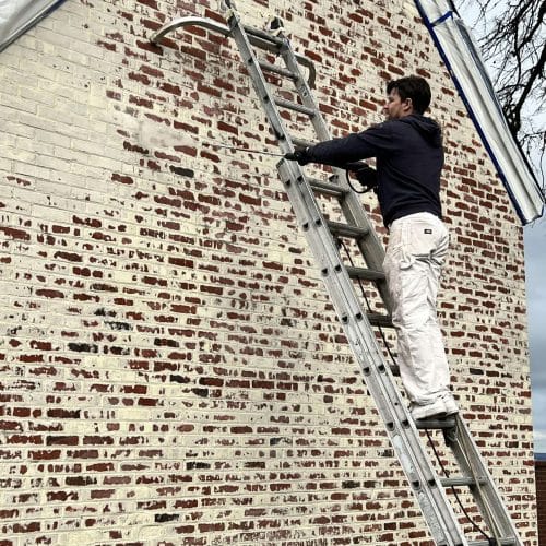 Removal of Limewash from exterior brick by using a power washer.